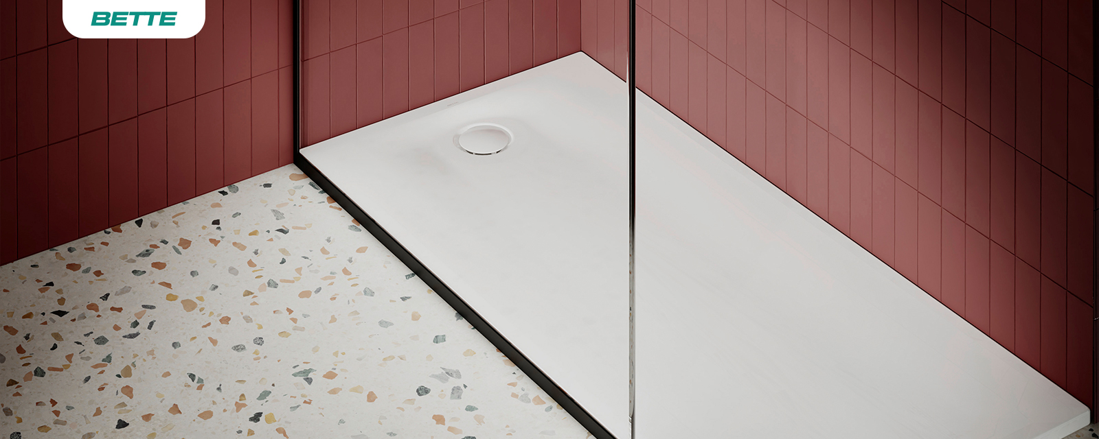 Bac à douche blanc extra-plat de marque BETTE dans une salle de bain moderne avec murs carrelés rouge foncé et sol en terrazzo.