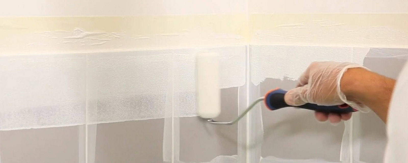 personne en train de peindre du carrelage avec un rouleau