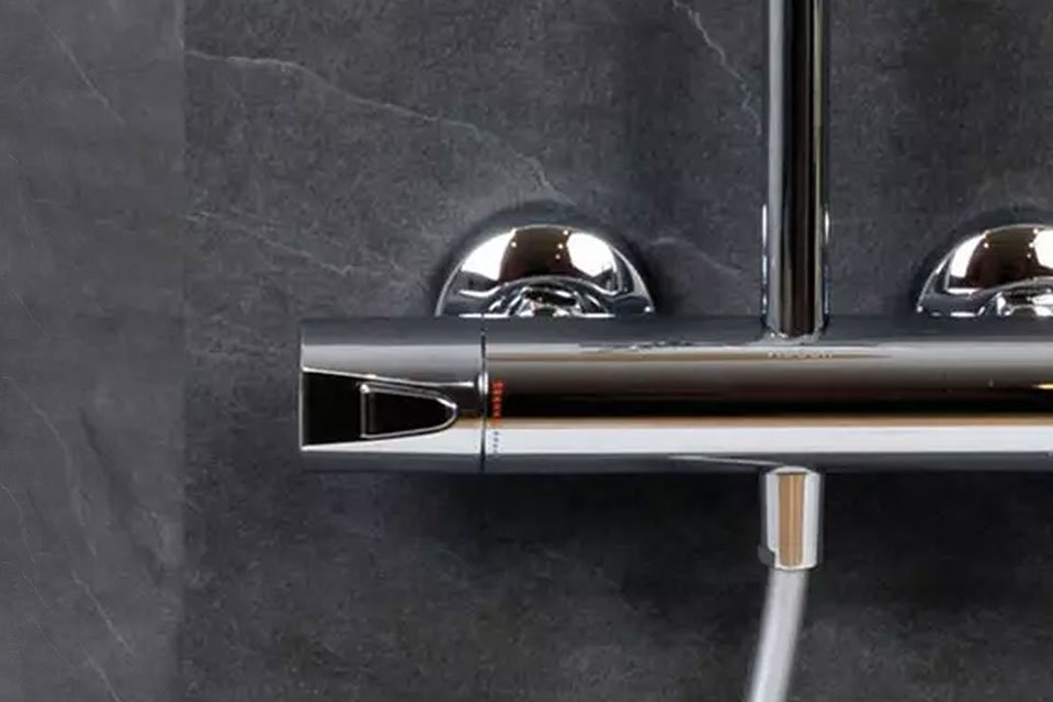 colonne de douche thermostatique chromée installée sur un mur gris