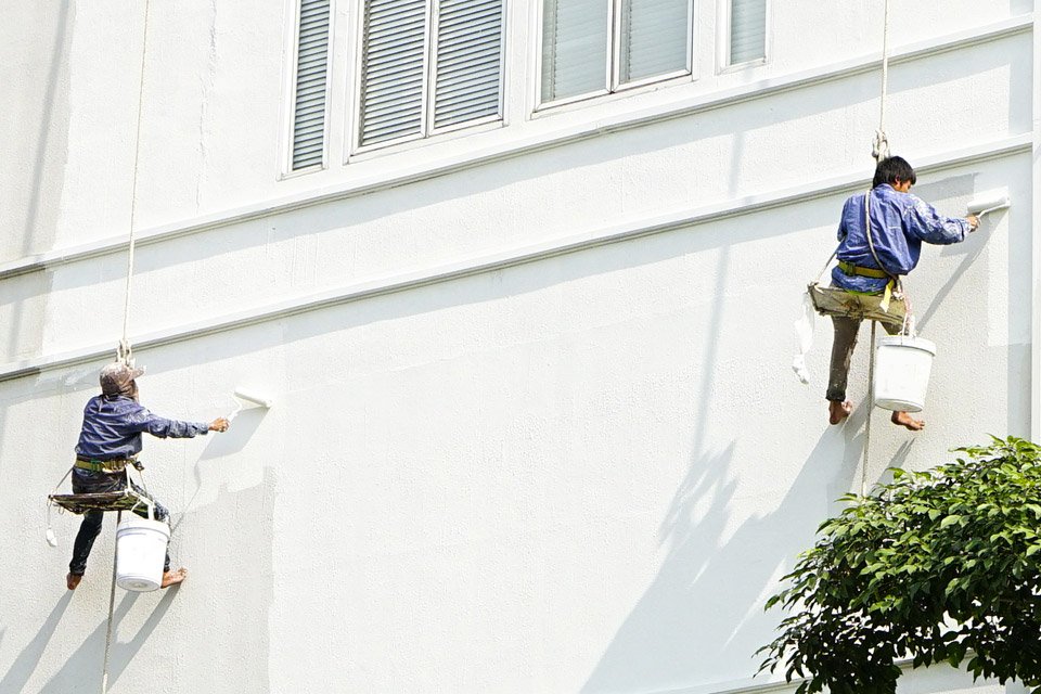 Deux professionnels qui opèrent le ravalement d'une façade