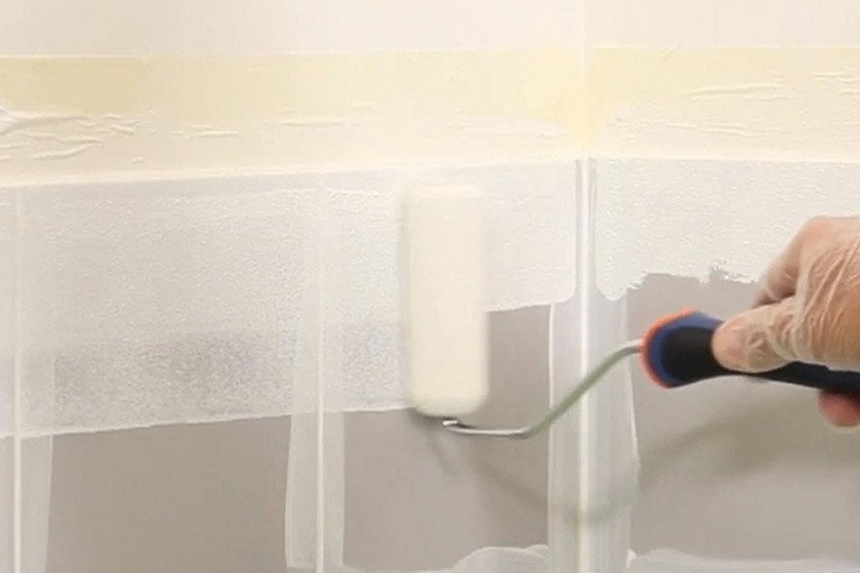 personne en train de peindre du carrelage avec un rouleau